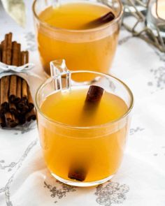 two glasses filled with liquid and cinnamon sticks