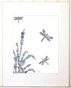 three dragonflies are flying in the sky above some rocks and plants with leaves on them