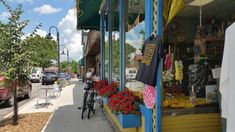 a bike is parked in front of a store on the side of the street with flowers