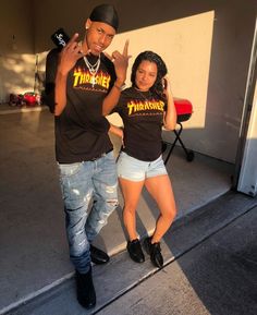 two people standing next to each other in front of a garage door with their fingers up