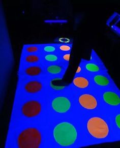 a person standing on top of a glowing floor with colorful dots in the middle of it