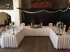 the tables are set up with white tablecloths and centerpieces on them