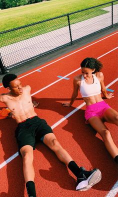 two young people sitting on a track with one laying down and the other standing up