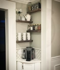 a corner shelf with coffee cups and mugs on it in the corner of a kitchen