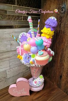 a vase filled with lots of cupcakes and candy on top of a table