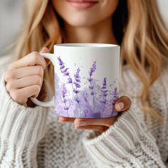 a woman holding a coffee mug with purple flowers on it