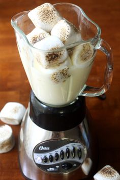 a blender filled with marshmallows on top of a wooden table