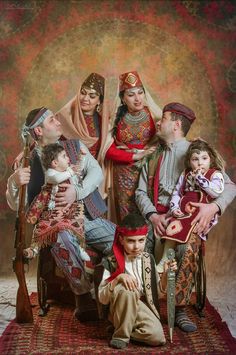 a group of people posing for a photo with their babies in traditional costumes and headgear