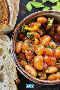 a bowl filled with beans next to some bread