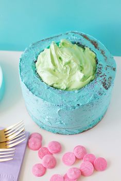 a blue cake with green frosting and pink candies next to it on a table