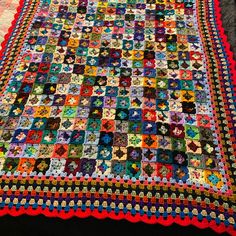 a multicolored quilt is laying on the floor next to a black table cloth