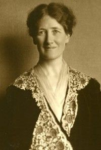 an old black and white photo of a woman wearing a dress with flowers on it