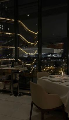 an empty restaurant table is lit up at night with the city lights in the background