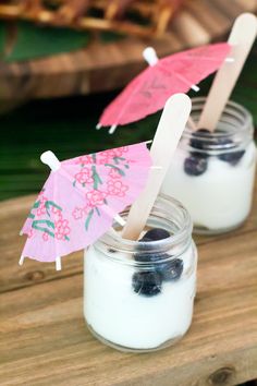 two mason jars filled with blueberries and marshmallows on a wooden table