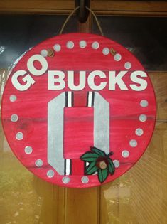 a red sign hanging from the side of a wooden door that says go buck's