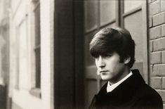 an old black and white photo of a young man standing in front of a building