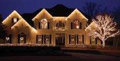 a large house with christmas lights on the front and side of it's windows