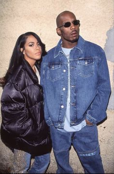 a man and woman standing next to each other in front of a wall with graffiti on it