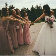 the bride and her bridesmaids are holding their hands out to each other in front of them