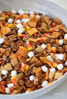 a white bowl filled with halloween cheetos and candy corn snack mix on top of a table