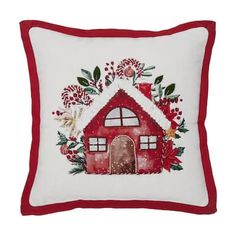 a red and white pillow with a small house on the front, surrounded by flowers