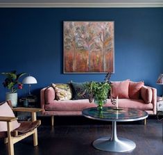 a living room filled with furniture and a painting on the wall above it's coffee table