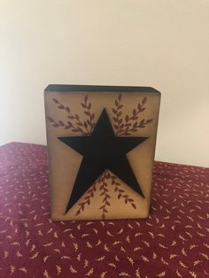 a wooden box with a black star on it sitting on a red tableclothed surface