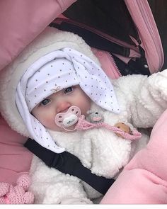 a baby in a stroller with a pacifier and blanket on it's head