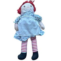 a doll with red hair wearing a blue dress and striped socks is standing in front of a white background