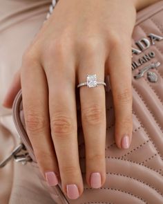 a close up of a person's hand with a ring on their finger, holding a pink purse