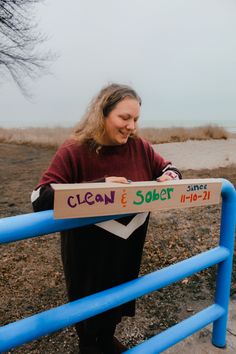 a woman is holding a sign that says clean and sobet in front of her