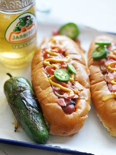 two hot dogs on buns with pickles and jalapenos next to them