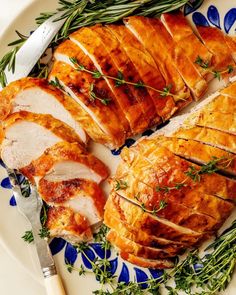 sliced chicken on a plate with herbs and utensils, ready to be eaten