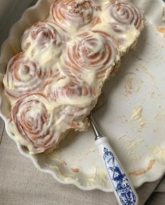 a white plate topped with a cake covered in icing next to a blue and white spatula