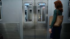 a woman standing in front of a silver train door