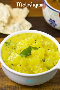 a white bowl filled with yellow food next to crackers