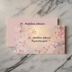 two business cards sitting on top of a marble surface with flowers in the middle and words above them that read dr maddiene johnson