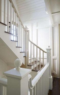 a white stair case in a house with wood floors and railings on both sides