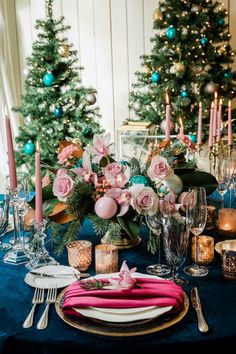 a table set for christmas dinner with pink and green flowers on the centerpieces