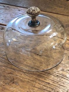 a glass cake plate with a lid on a wooden table