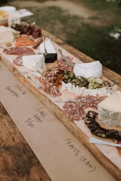 a wooden table topped with lots of different types of cheese and crackers on top of it