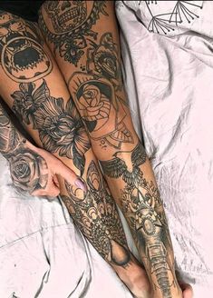 a woman laying on top of a bed covered in lots of tattooed leg tattoos next to a pillow