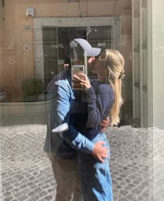 a man and woman taking a selfie in front of a building with their reflection