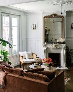 a living room filled with furniture and a fire place in front of a mirror on the wall