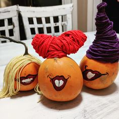 three pumpkins with faces painted on them sitting on a table next to each other