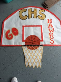 a basketball hoop with the words go hawks painted on it and someone's feet standing next to it