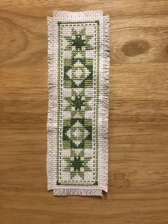 a piece of cloth with green and white designs on it sitting on top of a wooden table