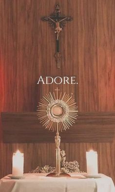 a table topped with candles next to a cross and an adore sign on the wall