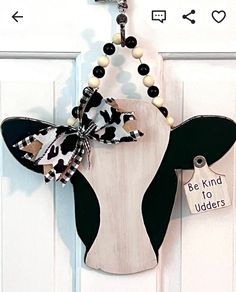 a cow head hanging on a door with a sign that says be kind to udders