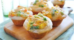 several small muffins on a cutting board with peas and carrots in them